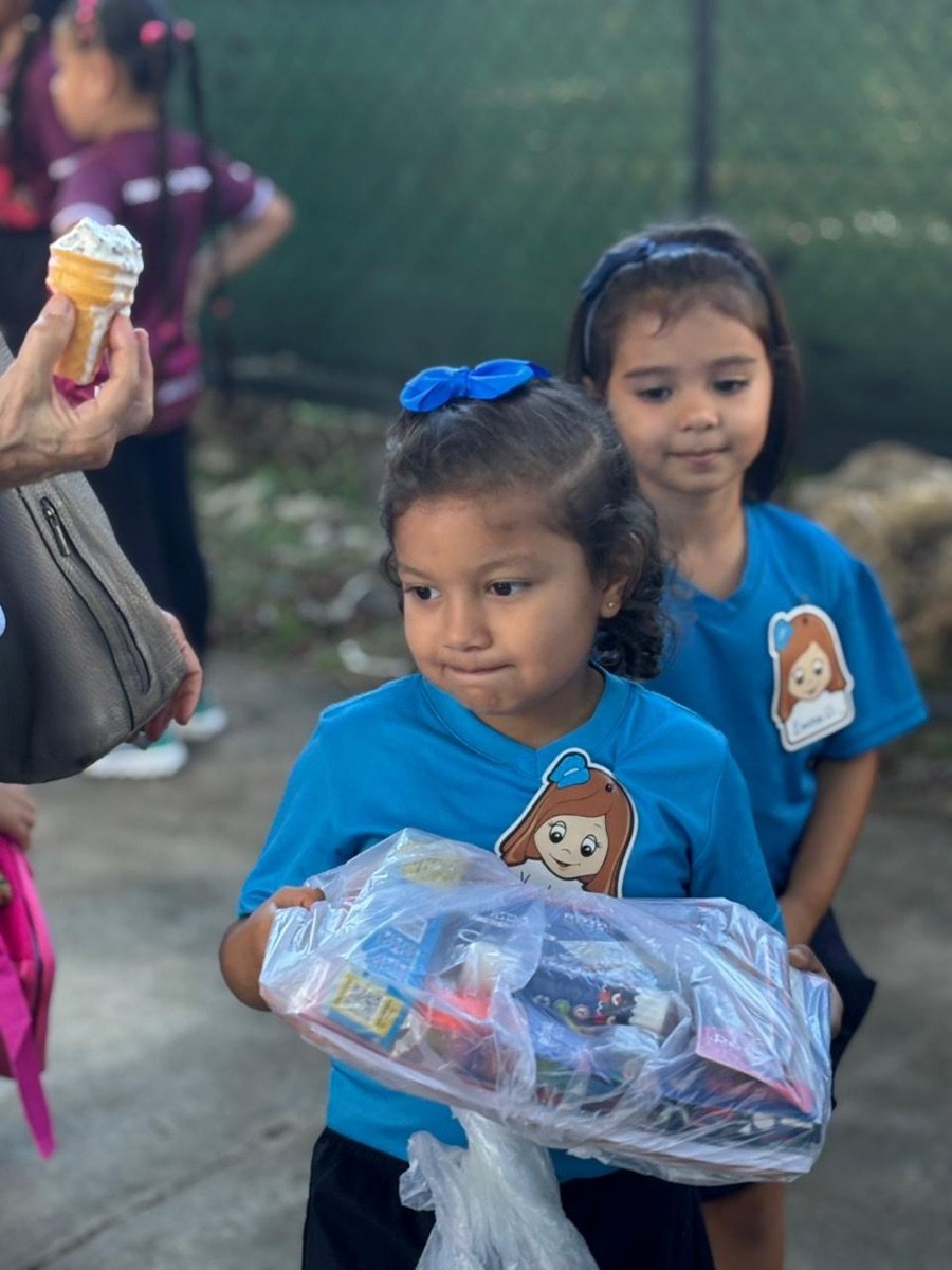 Niña con uniforme celebrando la entrega de su kit escolar